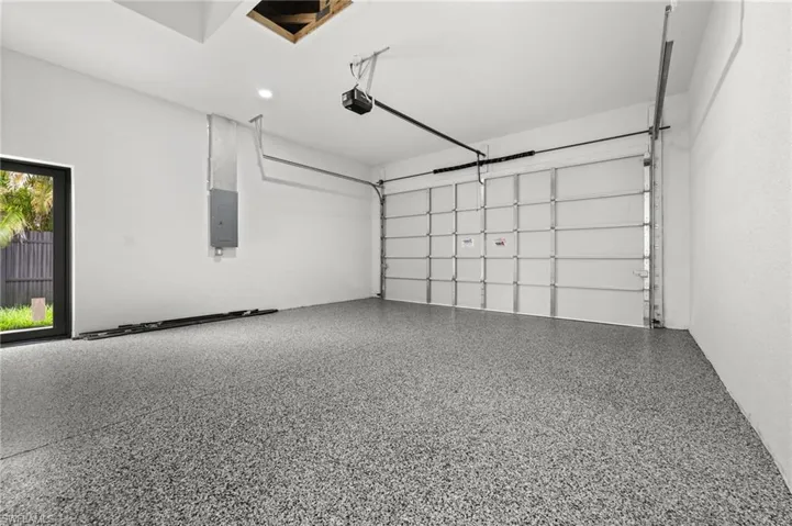 Spacious garage featuring a speckled epoxy floor, white walls, and an automatic garage door opener