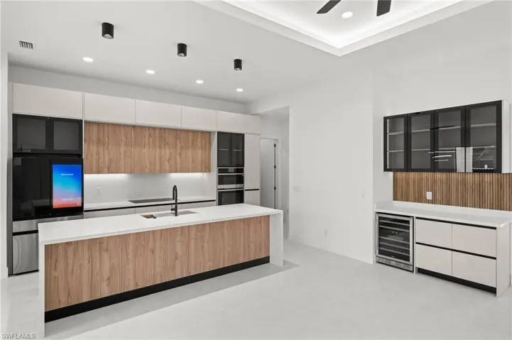Contemporary kitchen featuring a large island with wood-finish paneling, white quartz countertops, and integrated black sink with a matte black faucet
