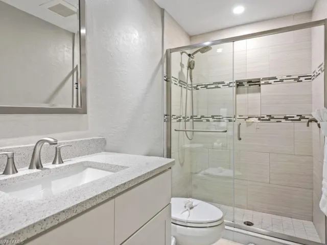 Full bath with a textured wall, vanity, and a stall shower