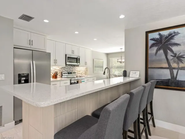 Kitchen with light stone countertops, appliances with stainless steel finishes, tasteful backsplash, hanging light fixtures, and recessed lighting