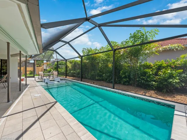 Swimming pool with a patio area, glass enclosure, and a sunroom