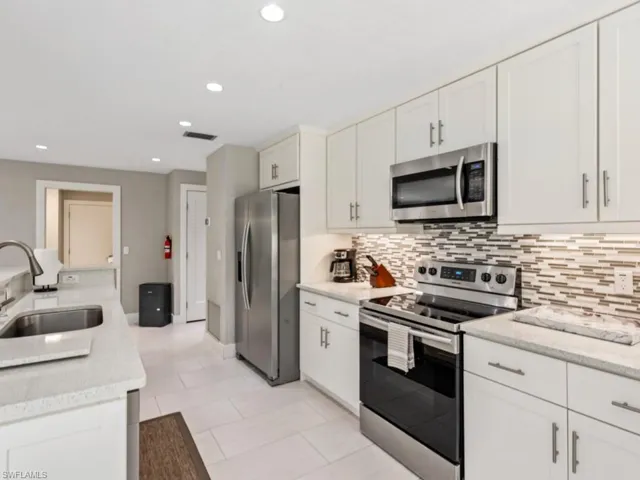 Kitchen with appliances with stainless steel finishes, white cabinets, recessed lighting, and backsplash