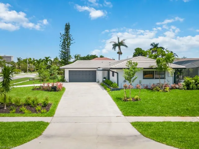 Ranch-style house with concrete driveway, a front yard, stucco siding, an attached garage, and a tile roof