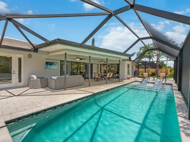 Outdoor pool featuring outdoor lounge area, a sunroom, a patio area, and glass enclosure
