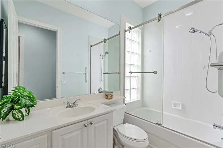 Full bathroom with vanity, enclosed tub / shower combo, and toilet.