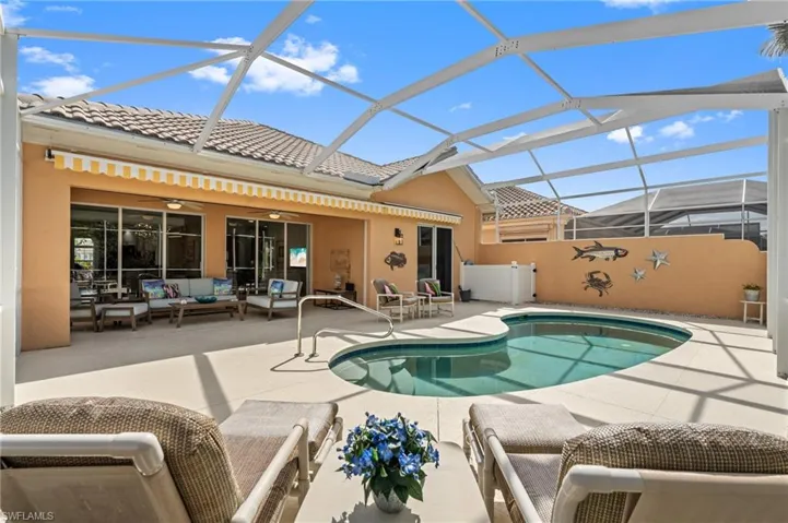 Rear view of house with a tiled roof, outdoor lounge area, stucco siding, and kidney pool.