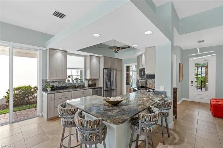 Kitchen with decorative backsplash, stainless steel appliances, sink, and stone countertops.