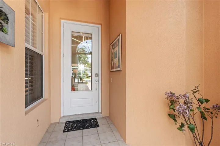 View of exterior entry featuring stucco siding and screened porch.