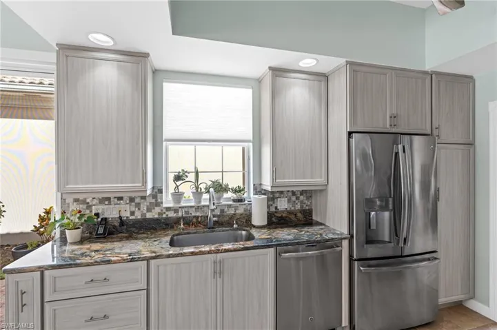 Kitchen with tasteful backsplash, stone countertops and recessed lighting.