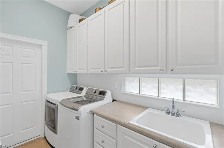 Laundry room with cabinet space, washer and clothes dryer, and convenient sink.