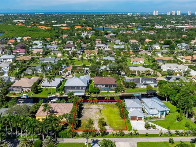 Aerial perspective of suburban area featuring property parcel outlined and a nearby body of water