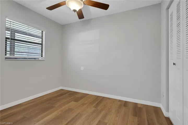 Unfurnished bedroom featuring wood finished floors, a closet, and a ceiling fan