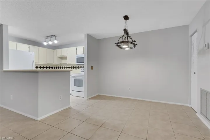 Kitchen featuring white appliances, pendant lighting, a textured ceiling, a peninsula, and a chandelier