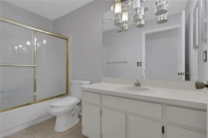 Full bathroom with vanity, shower / bath combination with glass door, and light tile patterned flooring