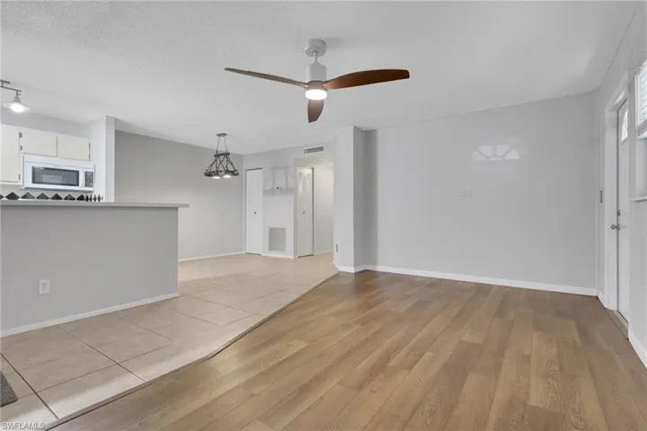 Unfurnished living room featuring light wood finished floors, a chandelier, a ceiling fan, and a textured ceiling