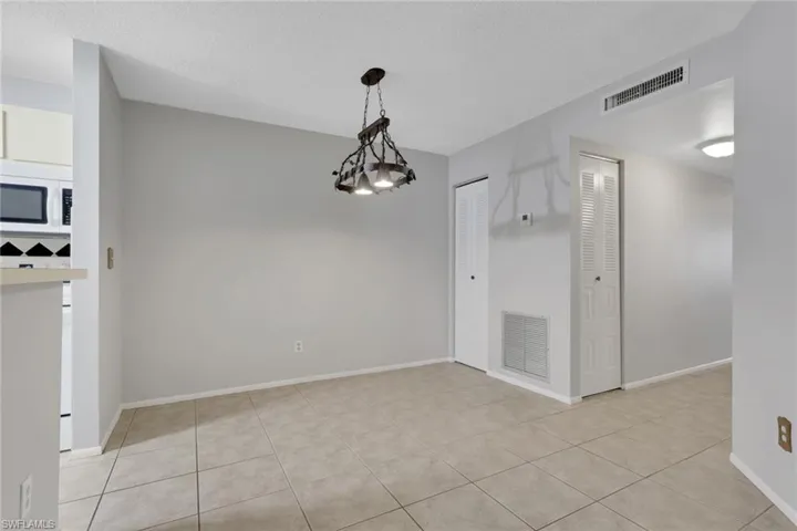 Unfurnished dining area with a chandelier, a textured ceiling, and light tile patterned floors