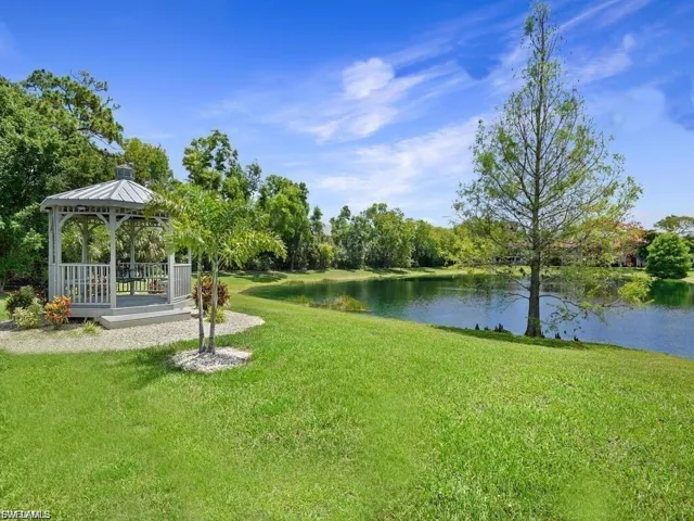 View of grassy yard featuring a gazebo and a deck with water view