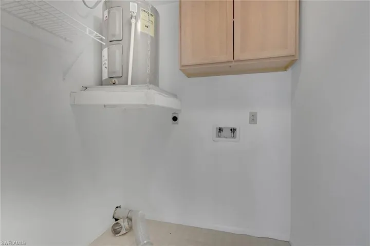 Laundry area with water heater, light floors, electric dryer hookup, cabinet space, and washer hookup