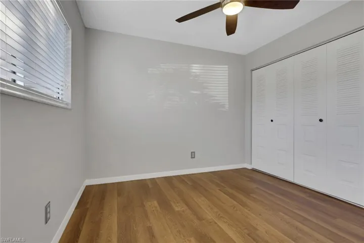 Unfurnished bedroom featuring wood finished floors, a ceiling fan, and a closet