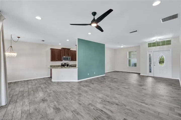 Unfurnished living room featuring hardwood / wood-style floors and ceiling fan with notable chandelier