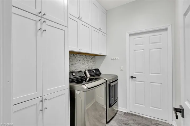 Washroom featuring washer and clothes dryer, cabinets, and light wood-type flooring