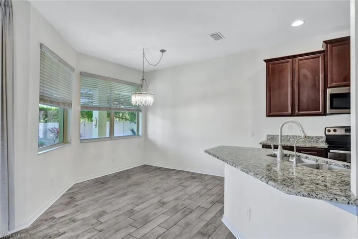 Kitchen featuring light stone countertops, stainless steel appliances, sink, a chandelier, and light hardwood / wood-style floors