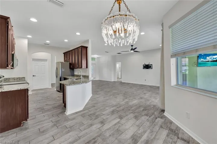 Kitchen featuring appliances with stainless steel finishes, light stone counters, sink, decorative light fixtures, and light hardwood / wood-style flooring