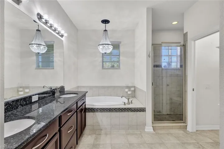 Bathroom featuring vanity, tile patterned flooring, plus walk in shower, and a notable chandelier