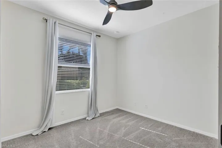 Carpeted empty room featuring ceiling fan