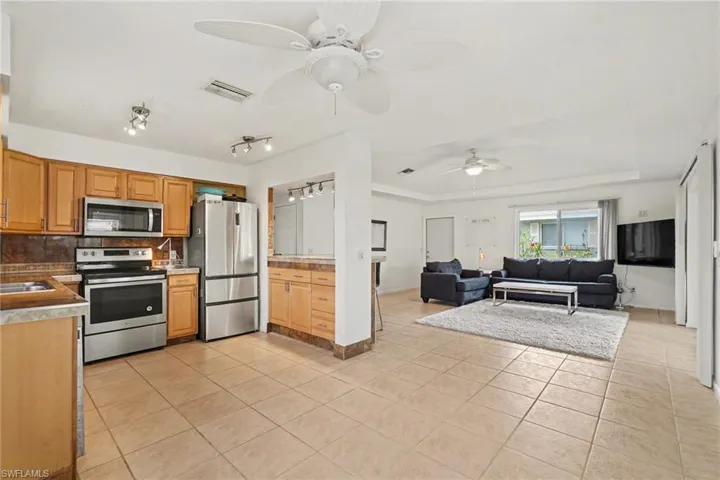 Kitchen featuring stainless steel appliances, light tile patterned flooring, a ceiling fan, and decorative backsplash