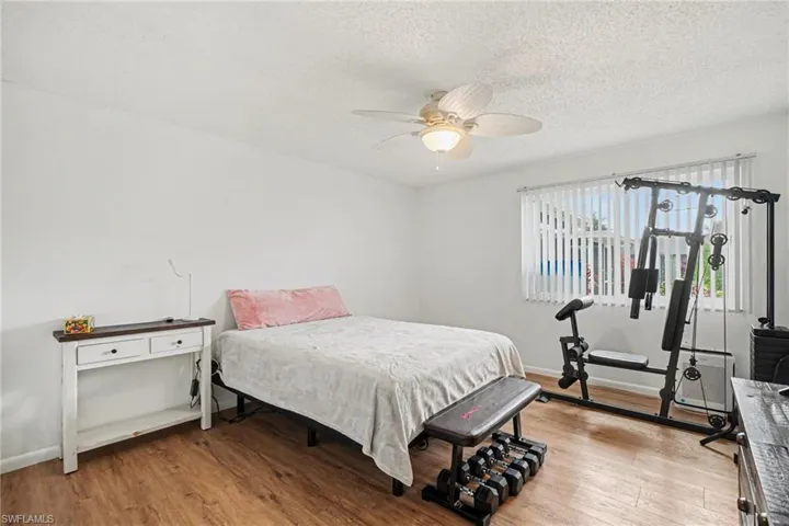 Bedroom with light wood finished floors, a ceiling fan, and a textured ceiling