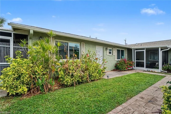 Back of house with stucco siding, a sunroom, and a yard