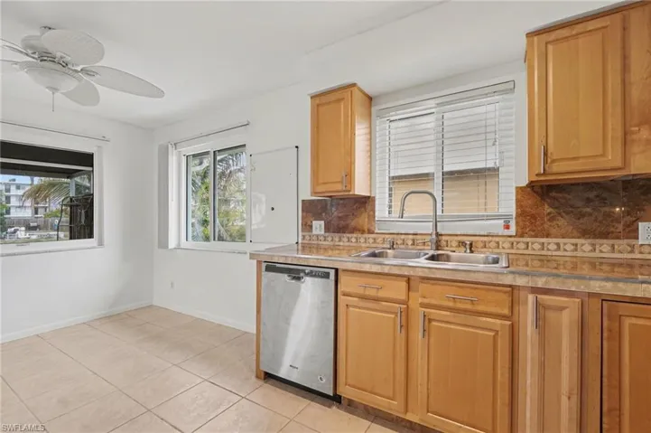 Kitchen with backsplash, stainless steel dishwasher, light countertops, ceiling fan, and light tile patterned floors