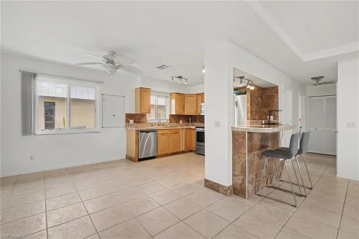 Kitchen with light countertops, ceiling fan, light tile patterned floors, and a kitchen breakfast bar