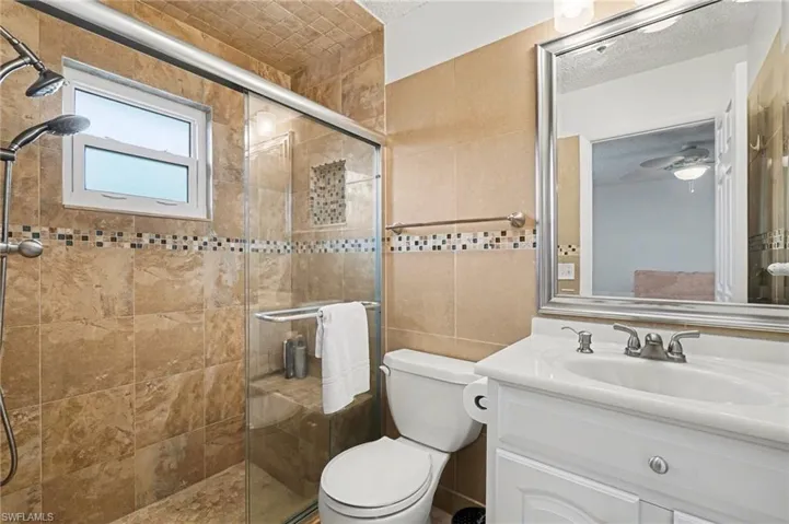 Bathroom with vanity, a stall shower, and tile walls