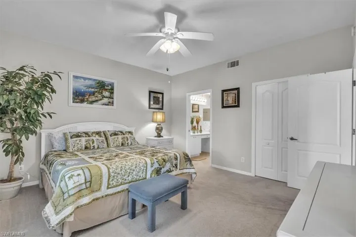 Bedroom featuring light carpet, a ceiling fan, and ensuite bath