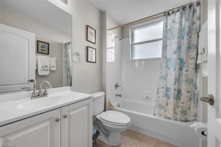 Full bathroom with shower / tub combo with curtain, vanity, and light tile patterned flooring