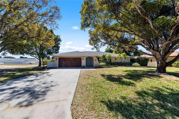 Ranch-style home featuring driveway, an attached garage, a front lawn, and stucco siding