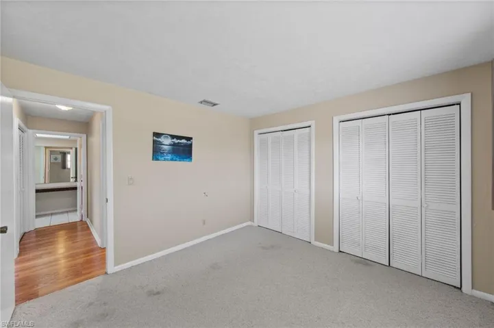 Unfurnished bedroom with multiple closets and light colored carpet