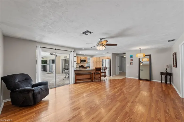 Living area with light wood-style floors, a ceiling fan, and a textured ceiling