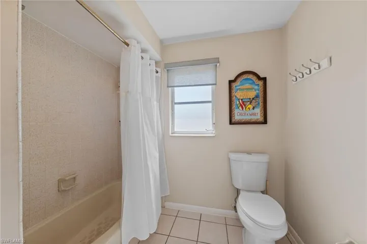 Full bathroom with shower / bath combo with shower curtain and light tile patterned flooring