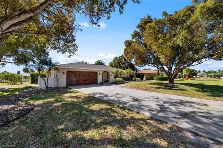 Ranch-style house featuring concrete driveway, stucco siding, a garage, and a front lawn