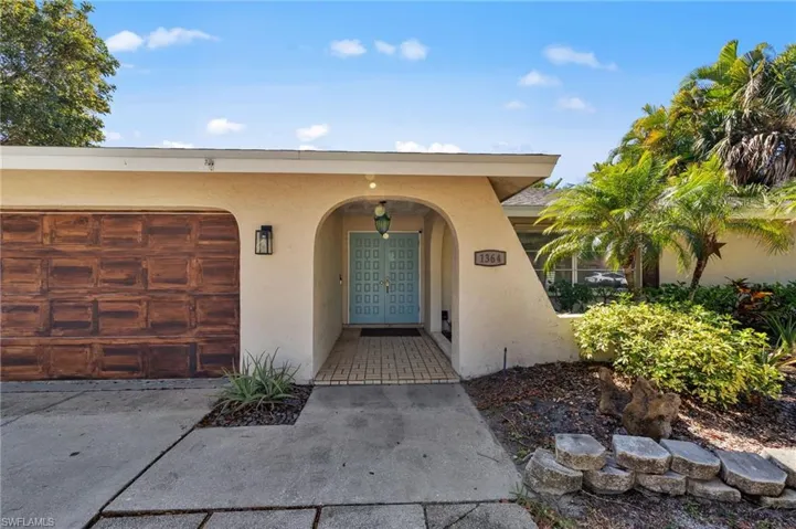 Doorway to property with stucco siding, driveway, and a garage