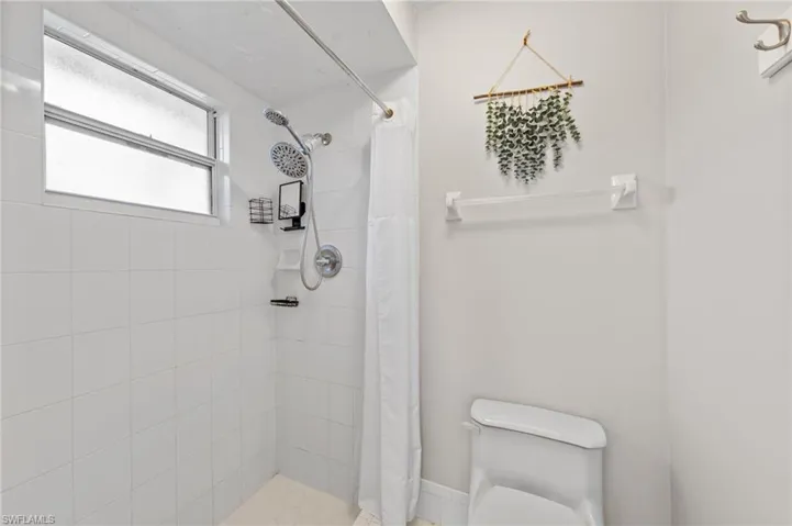Full bath featuring a stall shower and toilet