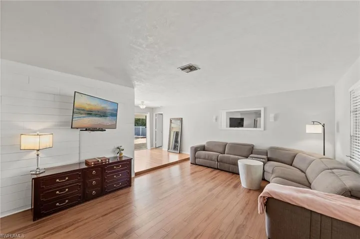Living area with light wood-type flooring, wood walls, a textured ceiling, and an accent wall