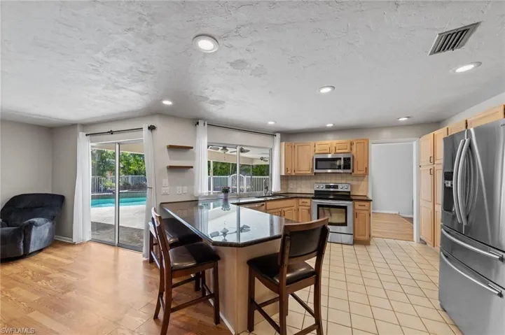 Kitchen with stainless steel appliances, open shelves, recessed lighting, backsplash, and a peninsula
