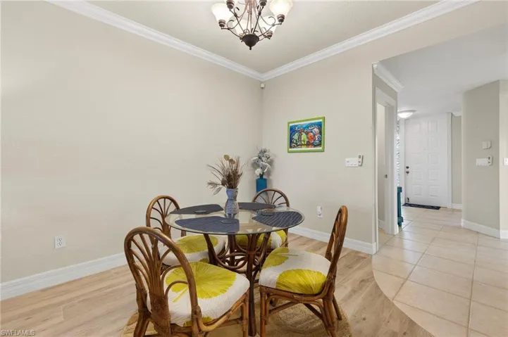Dining area with ornamental molding, light tile floors, and a chandelier