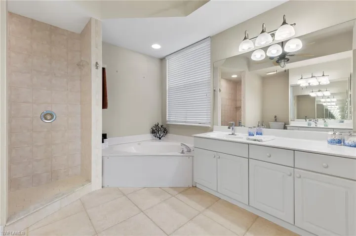 Bathroom with tile flooring, vanity, ceiling fan, and plus walk in shower