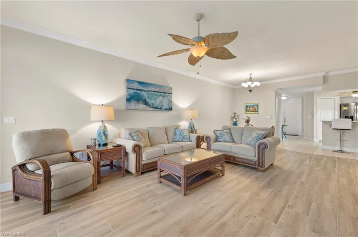 Living room featuring ceiling fan with notable chandelier and crown molding