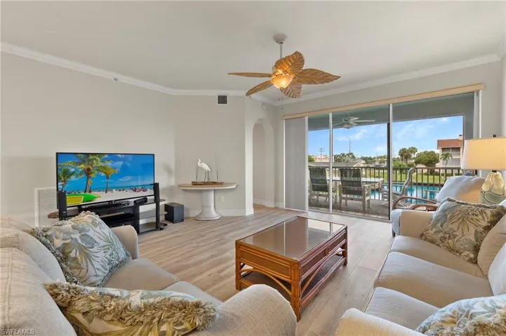 Living room featuring light hardwood / wood-style floors, ornamental molding, and ceiling fan